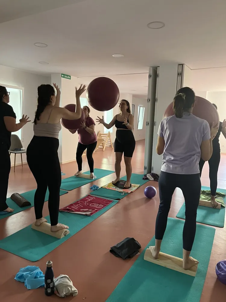 Grupo de embarazadas con pelotas y tablas de equilibrio en clase