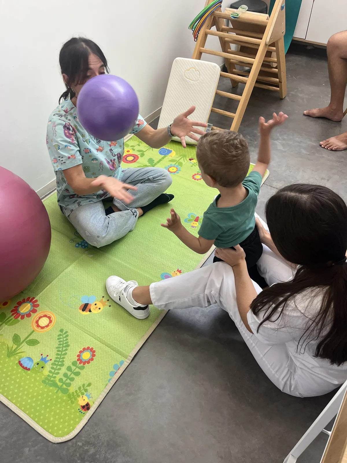 Niño jugando a la pelota con la fisioterapeuta pediátrica para trabajar equilibrio y coordinación