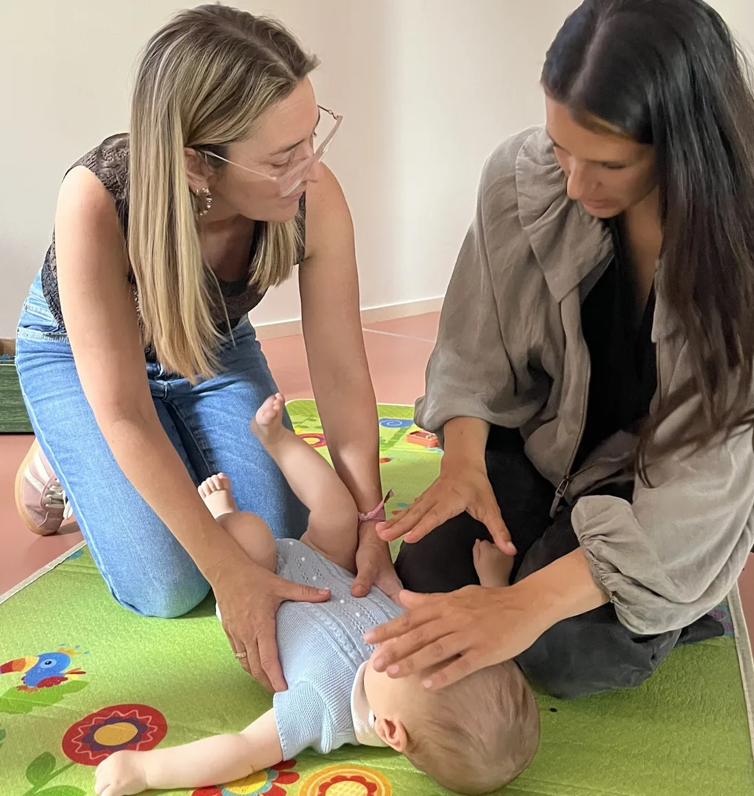 Dos madres con un bebé en la alfombra durante el taller babyfriendly de primeros auxilios pediátricos en Alicante