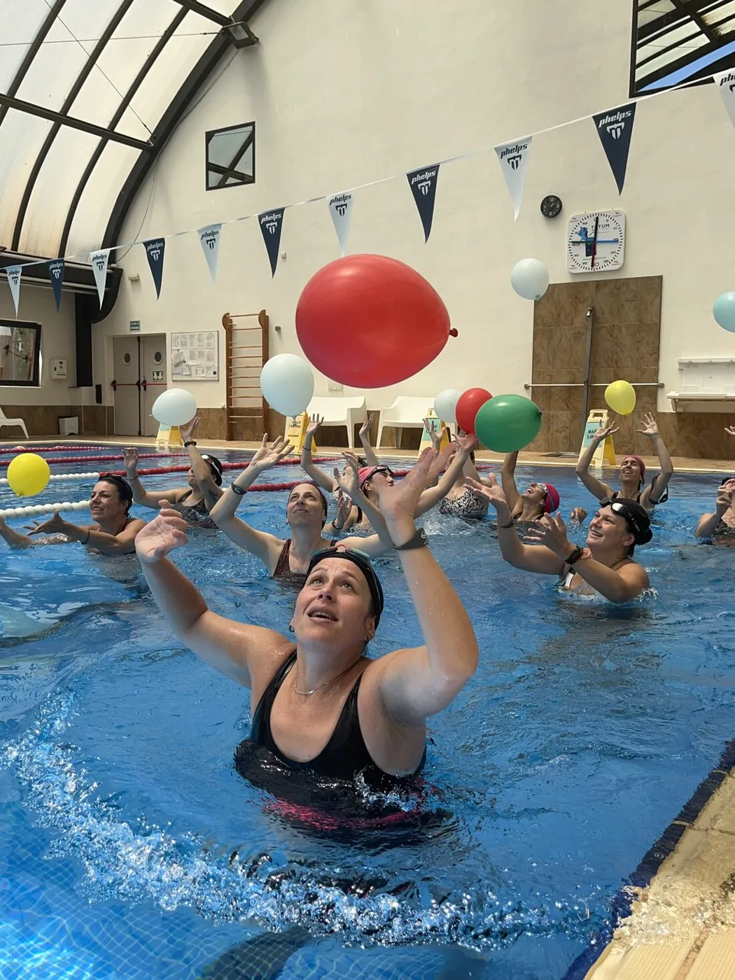 Mamás jugando con globos en la piscina durante una clase de matronatación