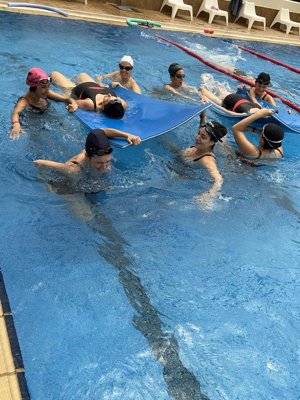 Embarazadas relajándose sobre colchonetas flotantes, sostenidas por sus compañeras
