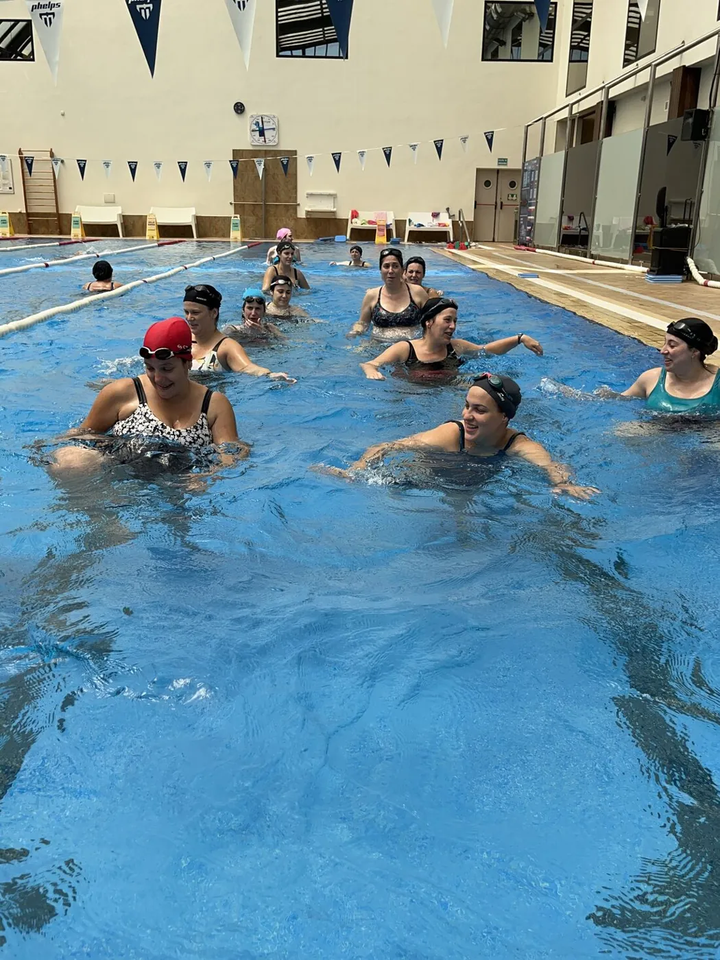 Grupo de embarazadas caminando en el agua y riendo en la piscina del Club Stadio
