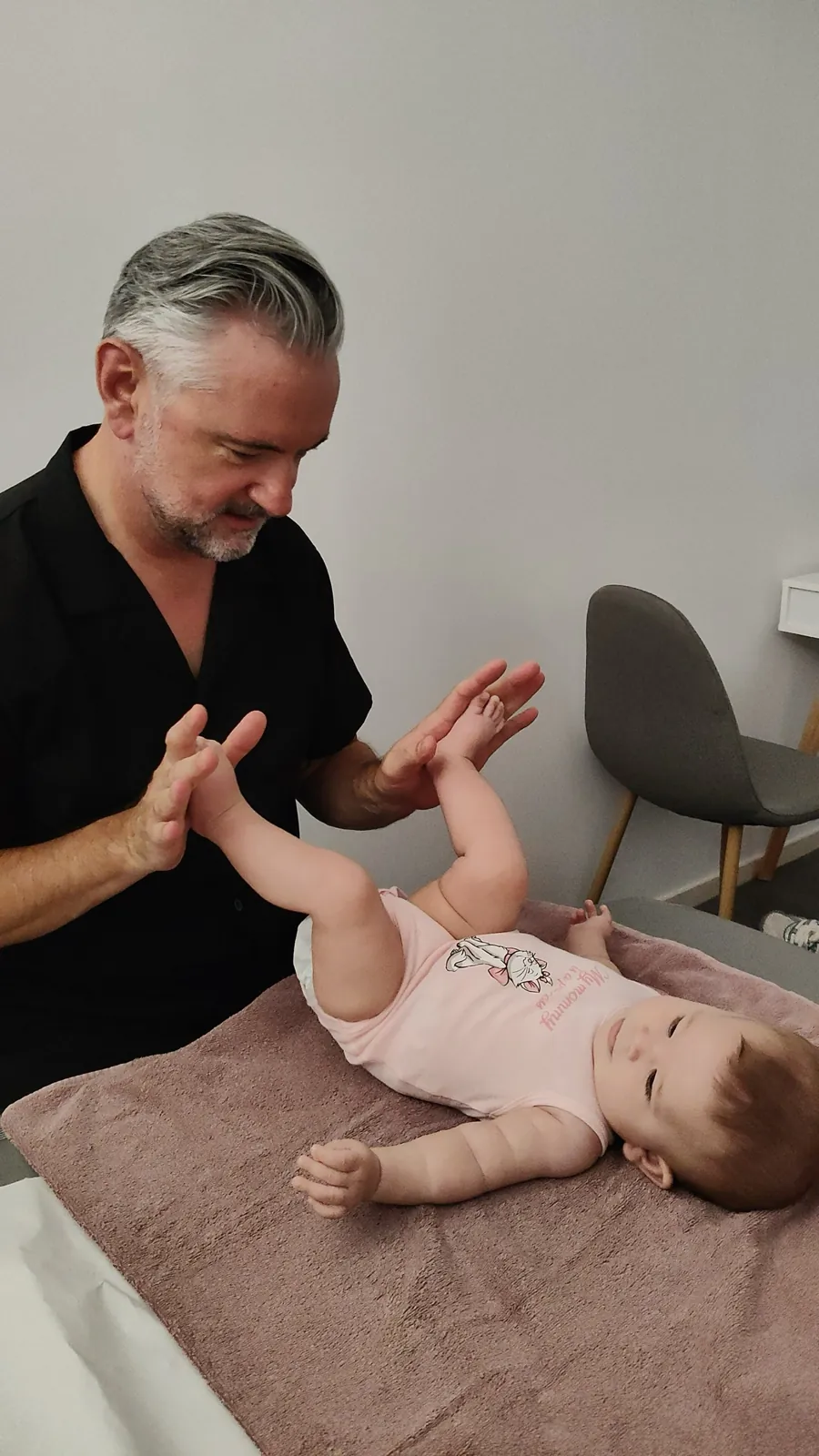 Bebé tranquila y atenta jugando durante la sesión de fisioterapia pediátrica