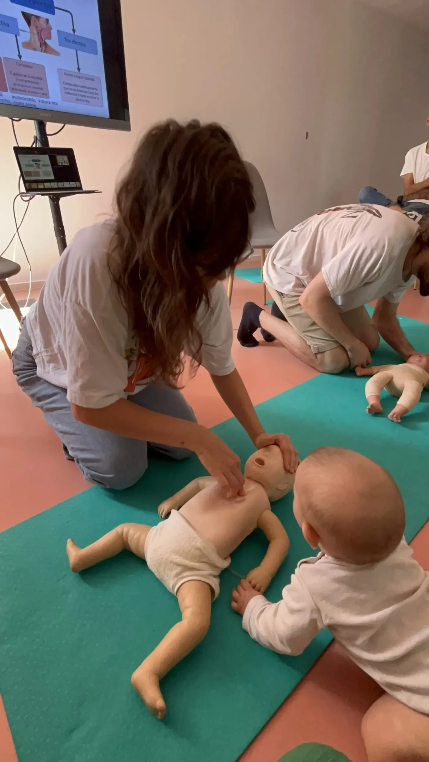 Familias practicando con muñecos de bebé en un taller de Mimando a Mamá